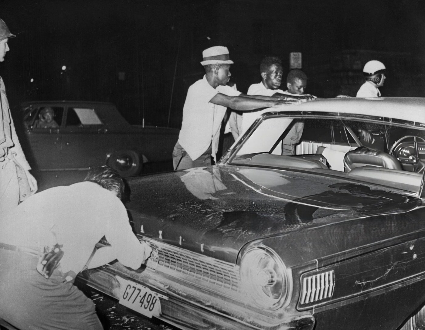 Suspected rioters place their hands on the roof of their car after they had been stopped by police during the riots