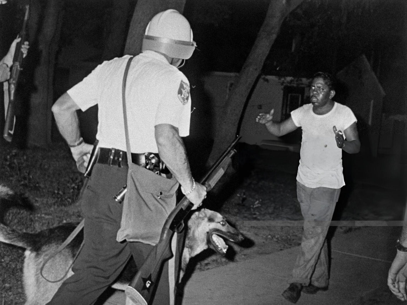 Helmeted police riot argue with an African american man as Newark witnessed its second night of rioting, 1960s.