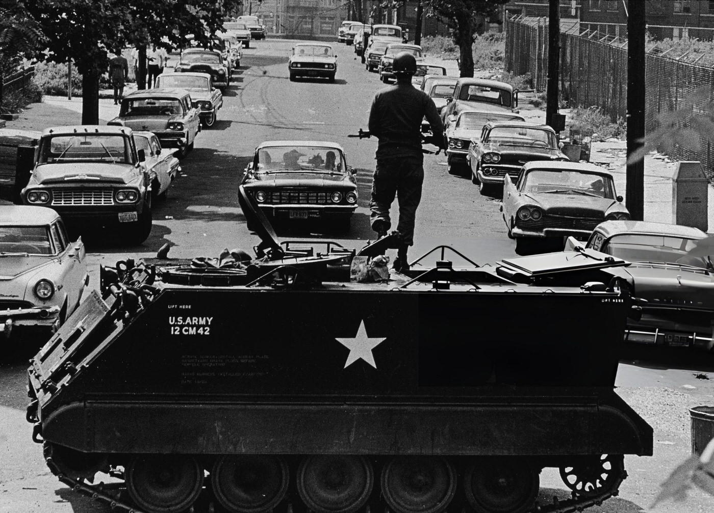 A National Guardsmen stands with a rifle atop a personnel carrier vehicle, blocking traffic leaving the area