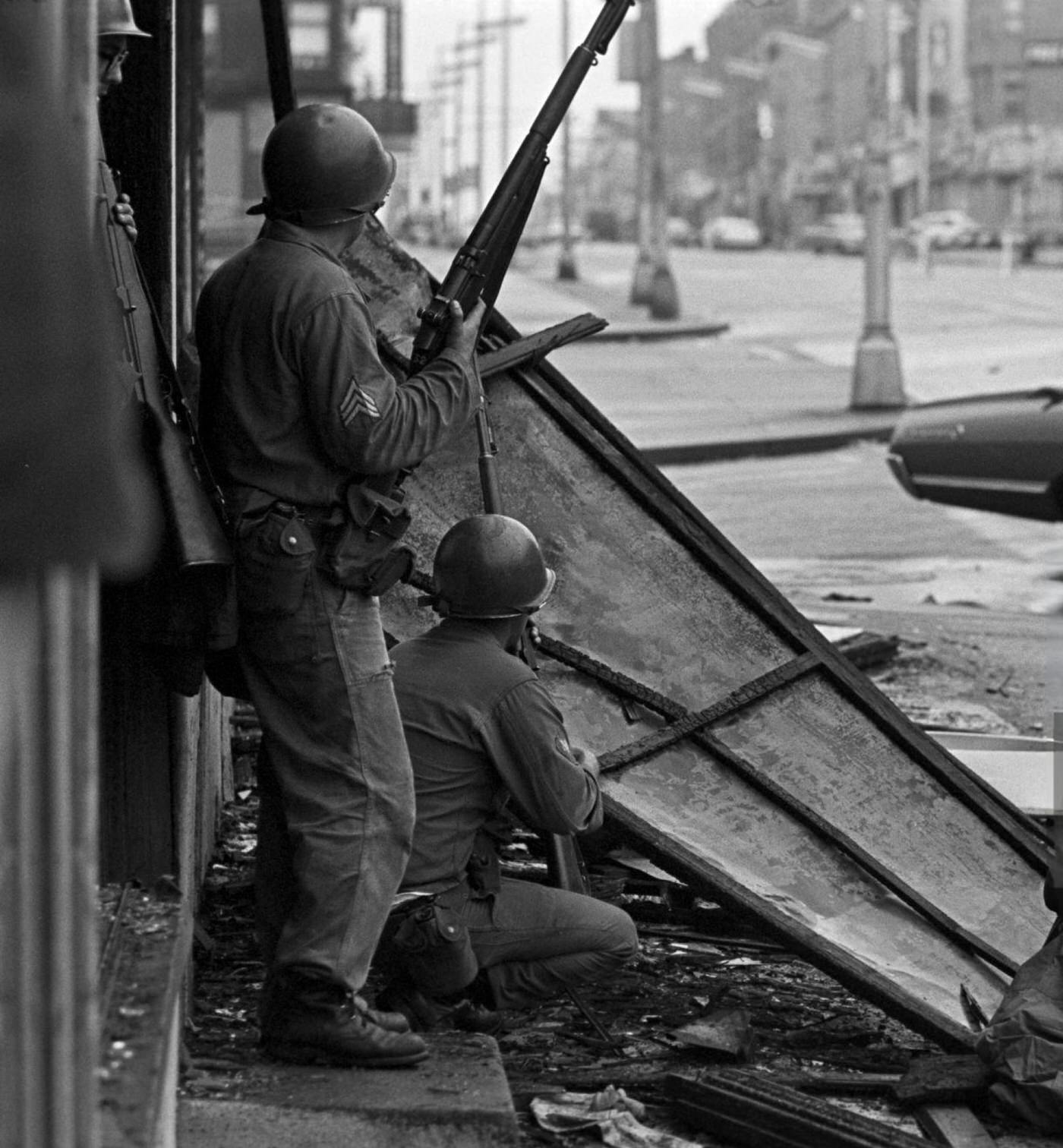 National Guard soldiers taking cover behind a fallen store sign