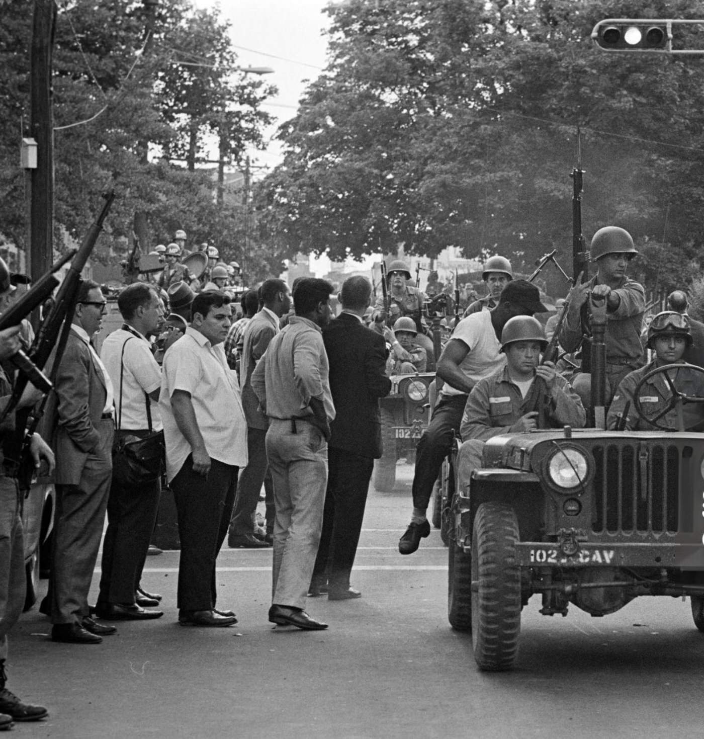 A regiment of the federal guard and state police driving jeeps in single file on an avenue