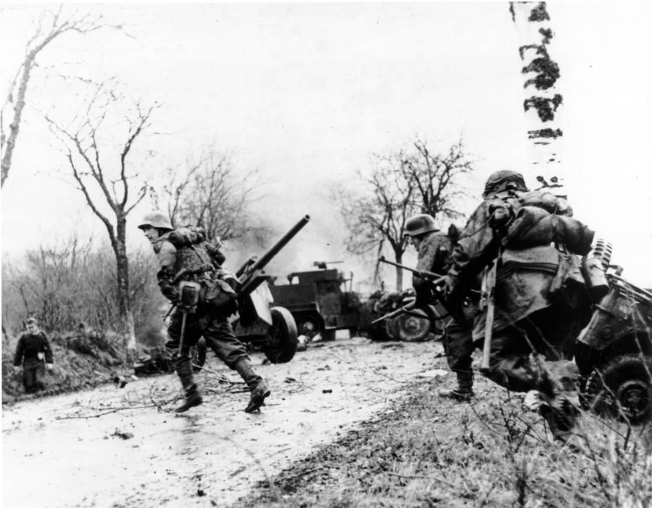 German troops advancing past abandoned American equipment during the Battle of the Bulge, 1944.