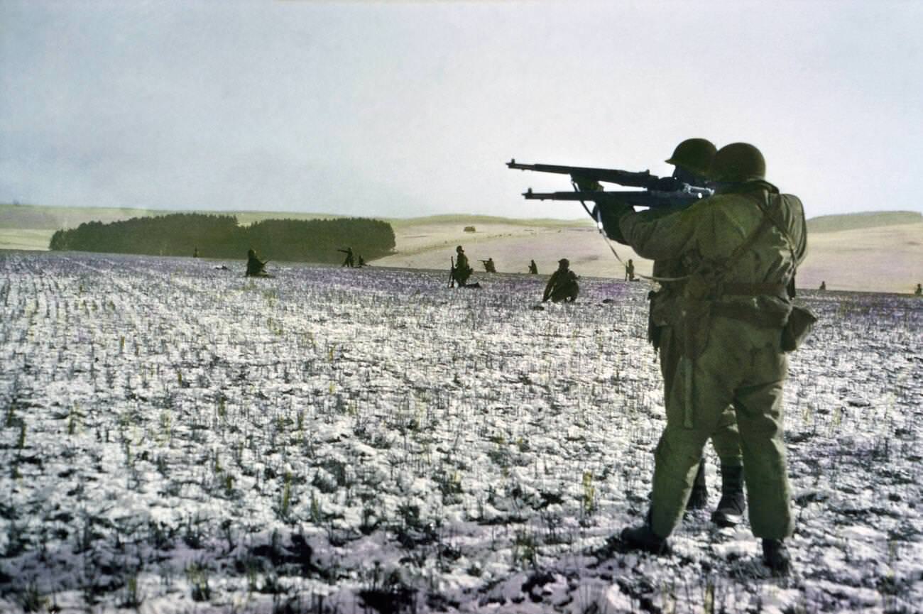 Infantrymen fire at German troops in advance to relieve surrounded paratroopers, Bastogne, Belgium, 1944.