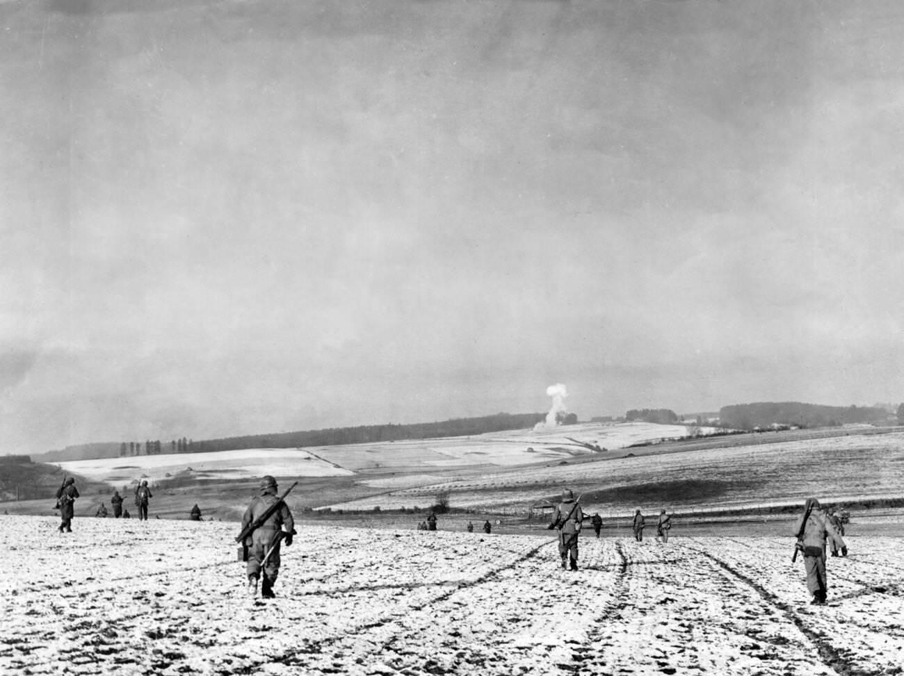 American soldiers advance across fields in the Bastogne area of the Ardennes, Belgium, during the Battle of the Bulge, 1944.