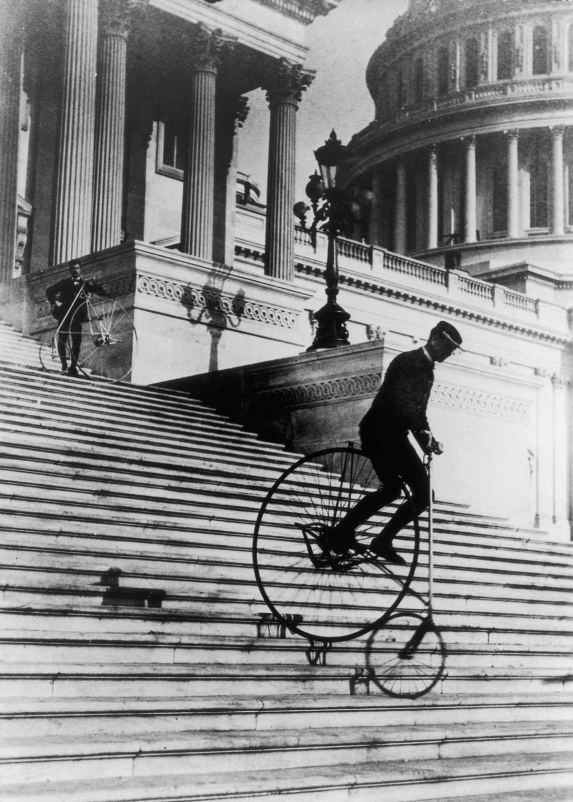 Men ride penny-farthings down the steps of the United States capitol building, 1895.