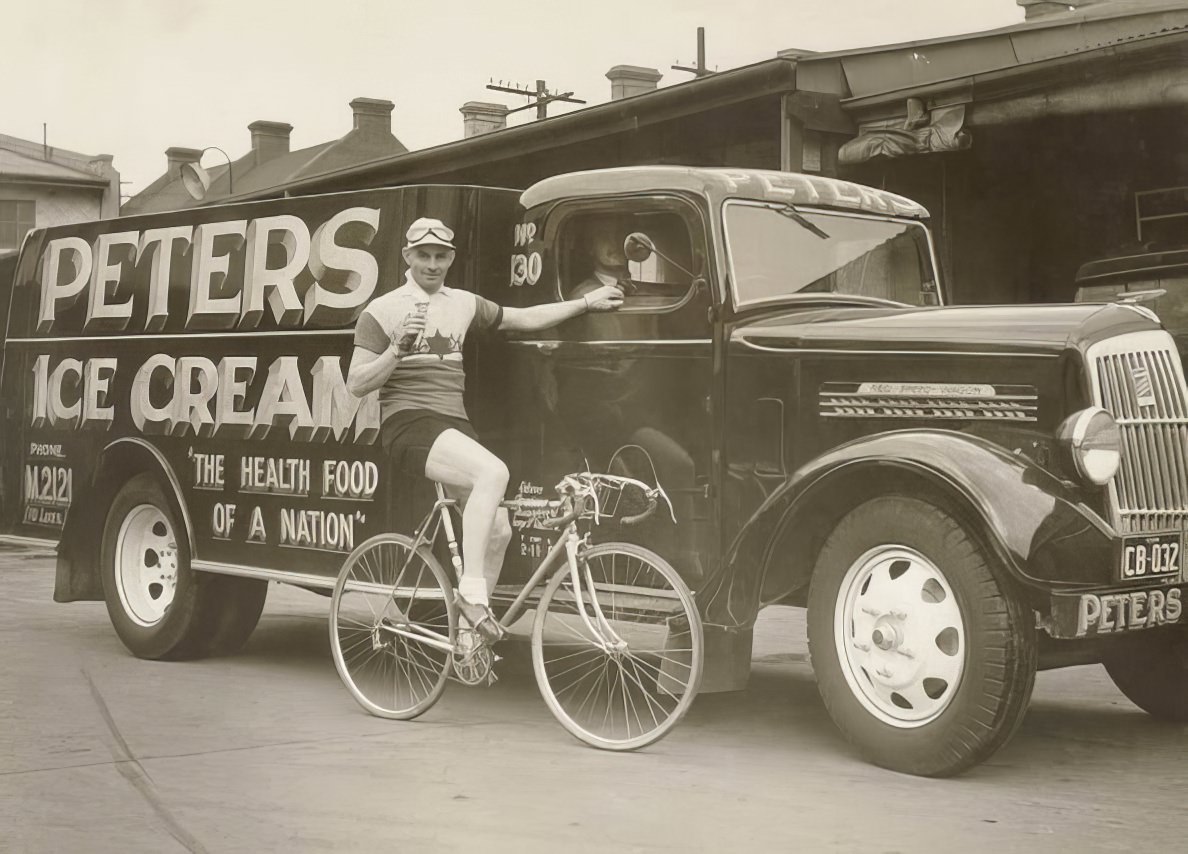 Hubert Opperman eating an ice cream next to a Peter's Ice Cream Reo truck, 1936.
