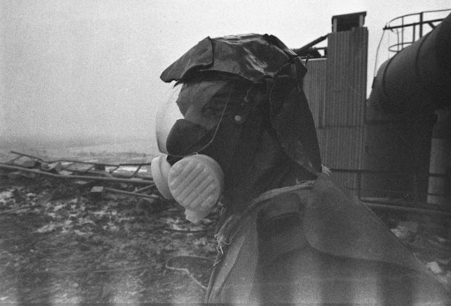 A liquidator, outfitted with handmade lead shielding on his head, works to clean the roof of reactor No. 3.