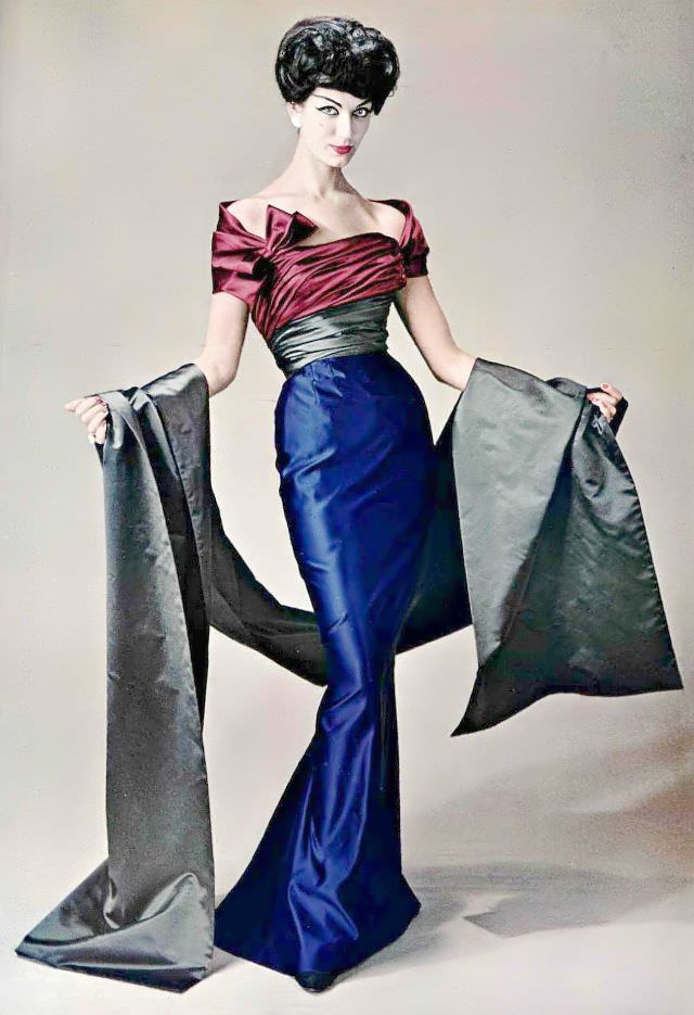 Simone d'Aillencourt in an exquisite satin evening gown in sapphire blue and garnet red, a sash and stole are in gray satin, by Pierre Balmain, 1957.
