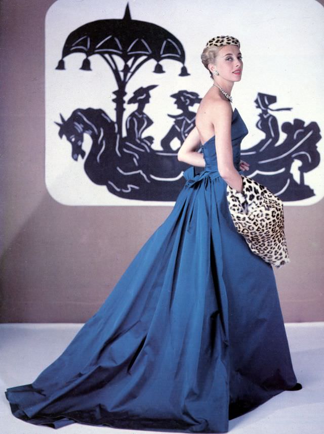 Balmain mannequin Marie-Thérèse models his evening gown accented with a leopard hat and muff, 1953.