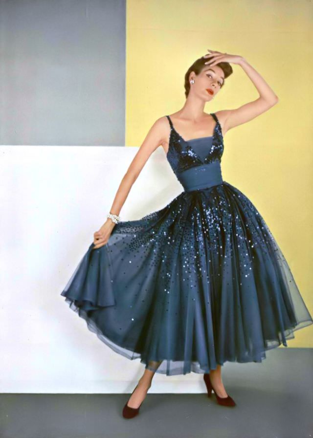 A model in a midnight blue chiffon dance dress strewn with sparkling sequins by Pierre Balmain, 1953.