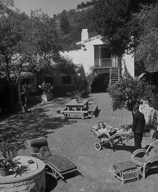 Bette Davis relaxing in a lounge chair with her Pekingese, Popeye the Magnificent, at her Beverly Hills home, 1939.