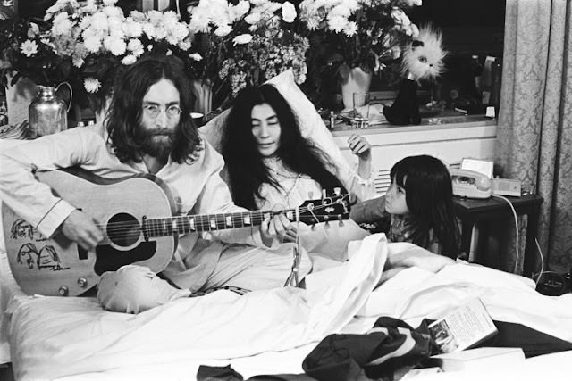 Kyoko Ono listens to John Lennon strum his guitar next to her mother, Yoko.