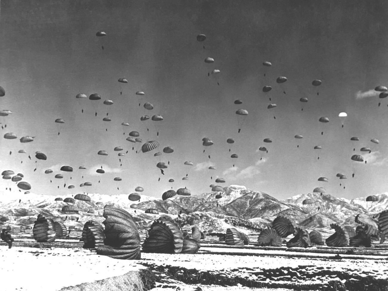 U.S. Army airborne soldiers and United Nations forces parachute during a combat operation, 1951.