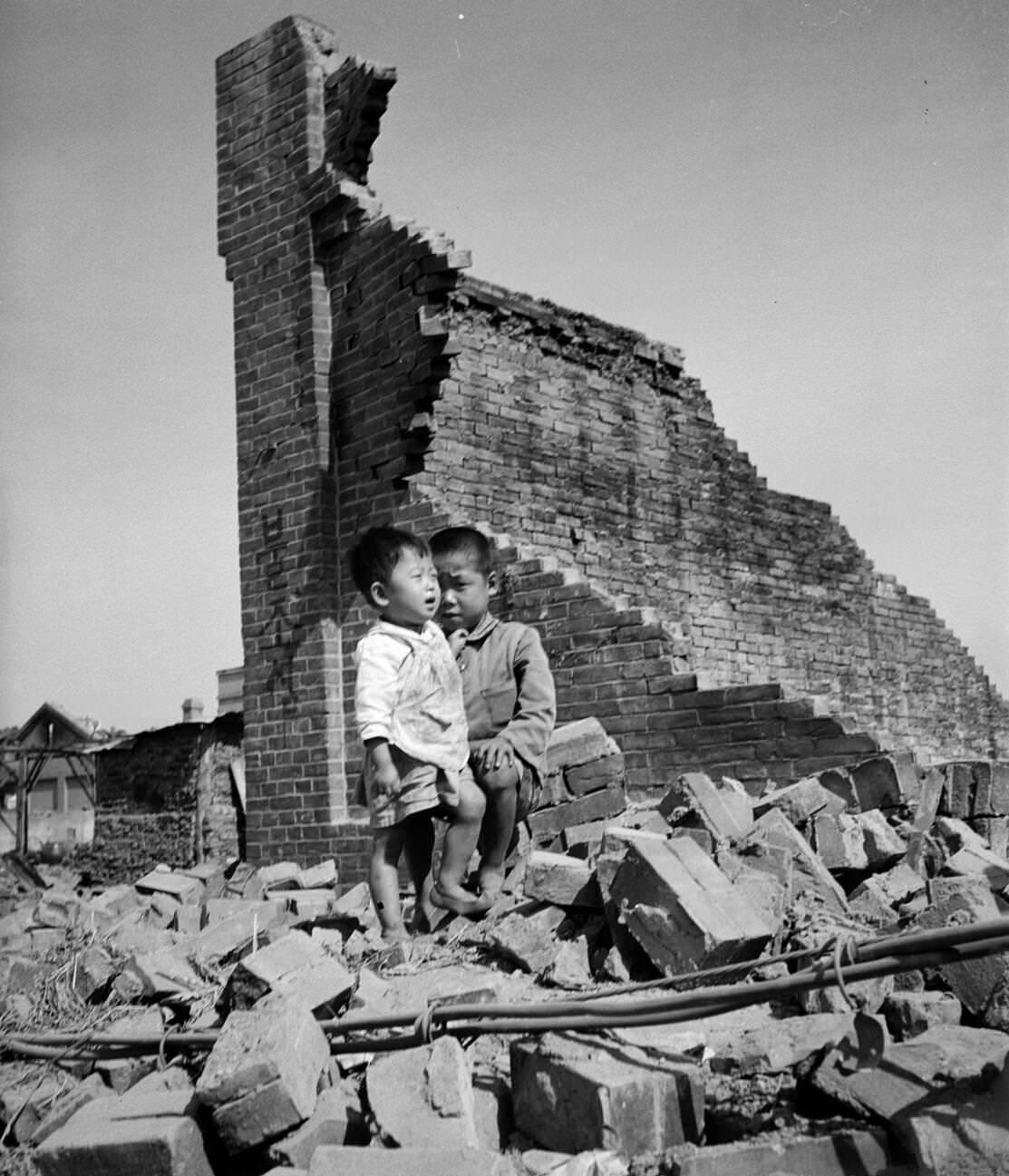 Two orphans lost in the ruins of Incheon during the Korean War, 1950s.