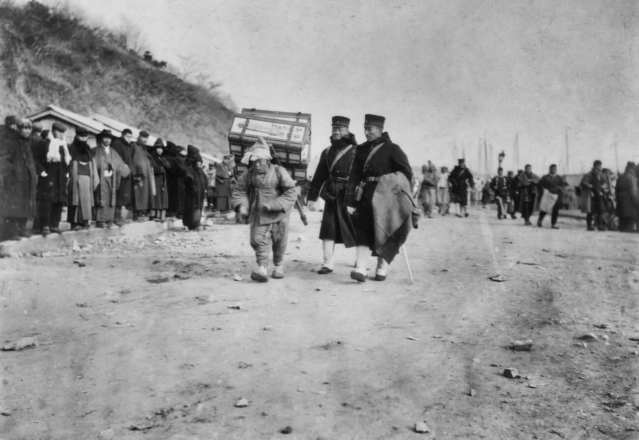 A Korean coolie carrying medical supplies from shore to hospital, 1904.