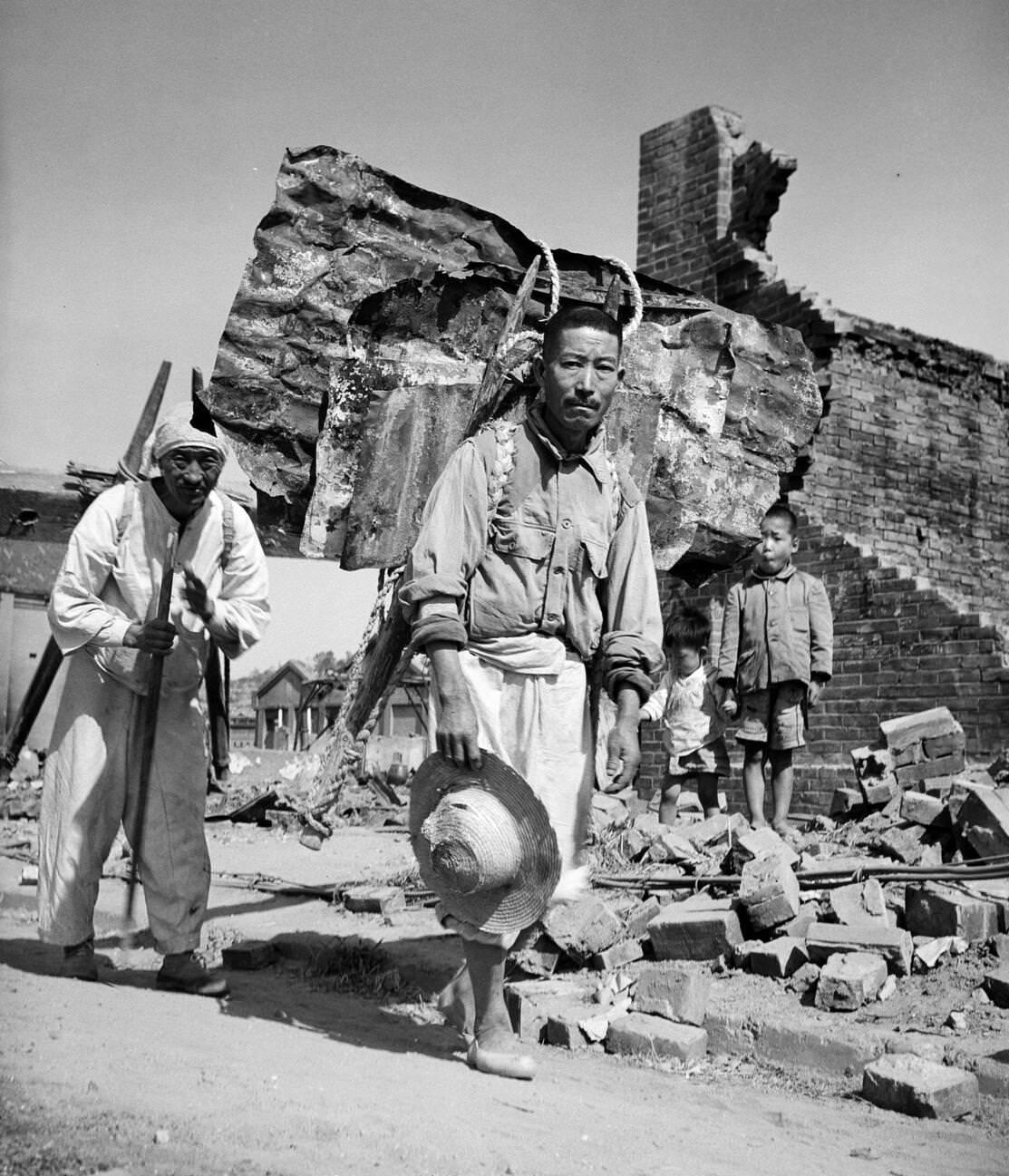 Civilians recovering building materials from the ruins in Inchon during the Korean War, 1950s.