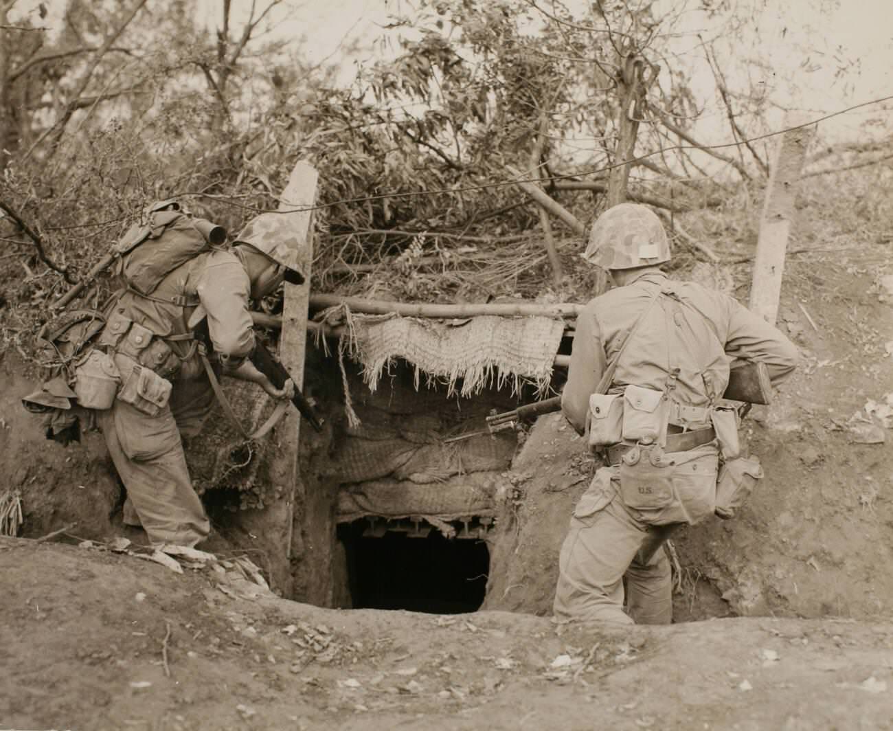 Marine privates stealthily approach the entrance of a Korean Communist dugout, 1950s.