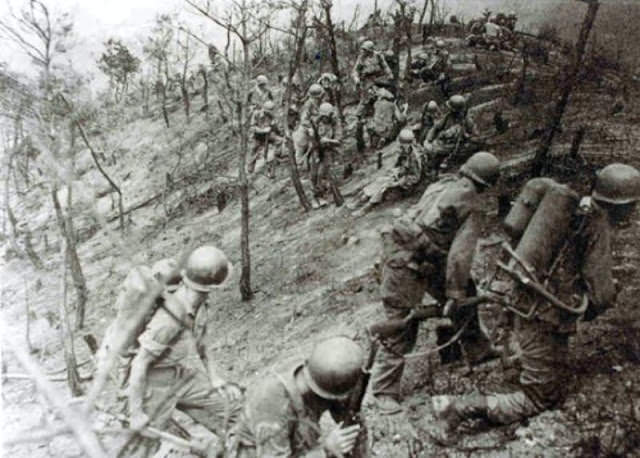 American flame thrower units advancing toward a tunnel entrance, 1950s.