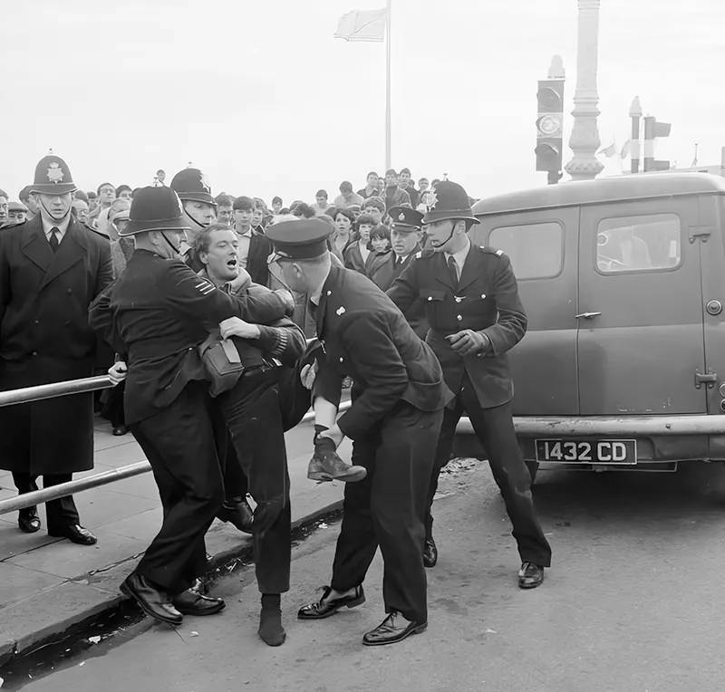Three police officers drag away a rocker who refuses to stop fighting in Brighton, England, 1965.