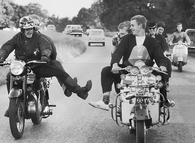 A rocker tries to kick over a rival mod's scooter in England, 1964.