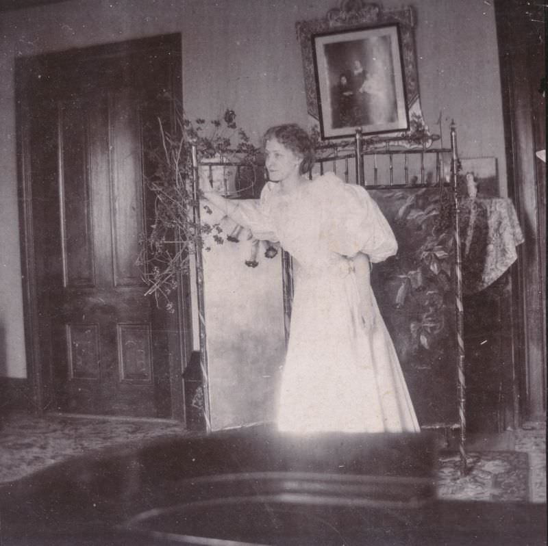 Woman in a dress hunches over in her bedroom