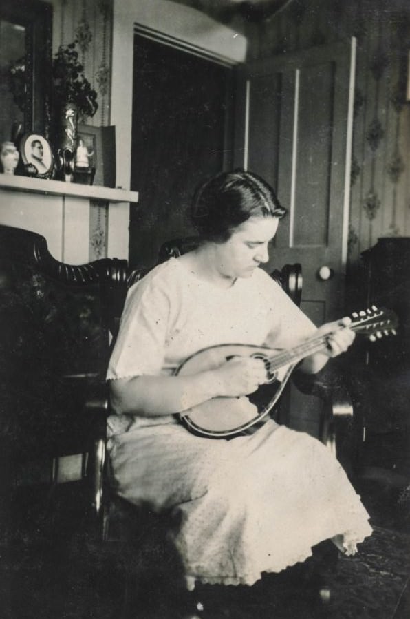 Woman plays a mandolin in her bedroom