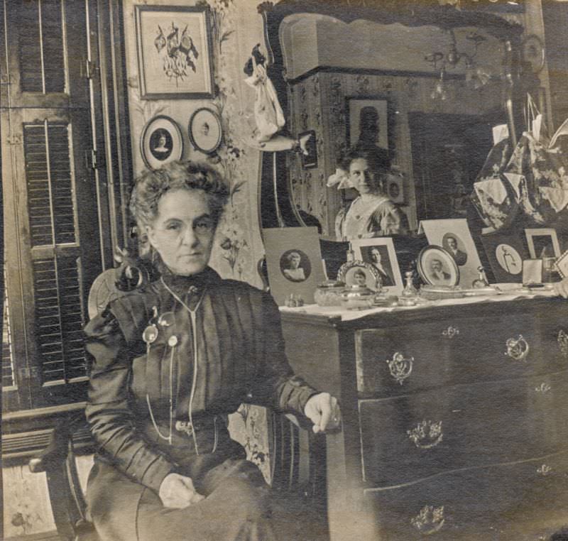 Woman sits next to a mirror with another watching on