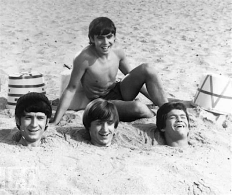 The Monkees (you can only see Davy Jones’ bathing suit, but we imagine Mike Nesmith, Peter Tork and Micky Dolenz have got them on under all that sand), 1967