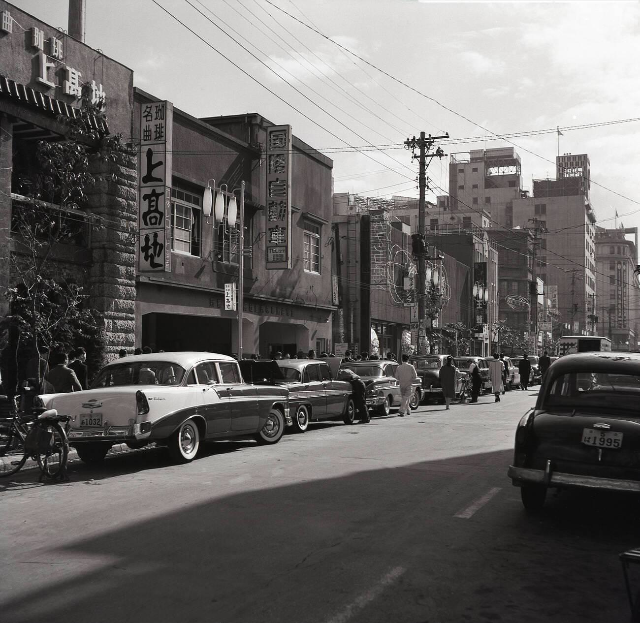 A street scene in Tokyo showing parked American style cars, 1950s.