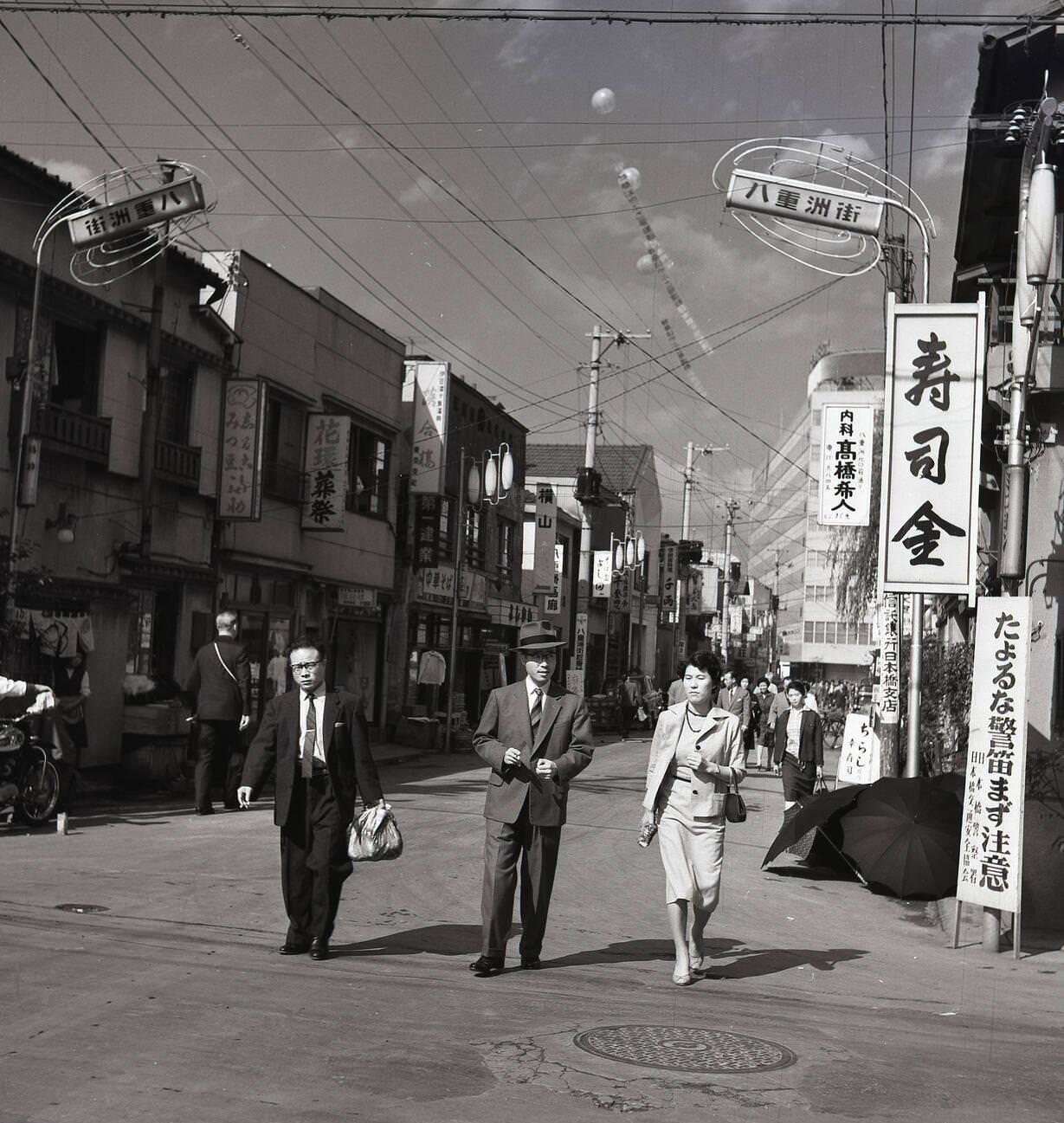Two businessmen and a lady walking through the old town district of Tokyo, 1950s.