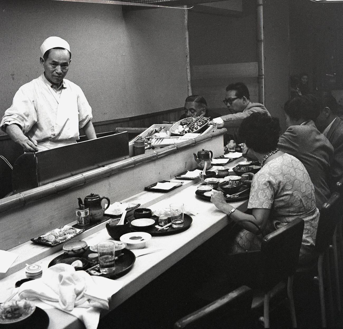 People having a meal sitting on barstools at a counter at a restaurant in Tokyo, 1950s.