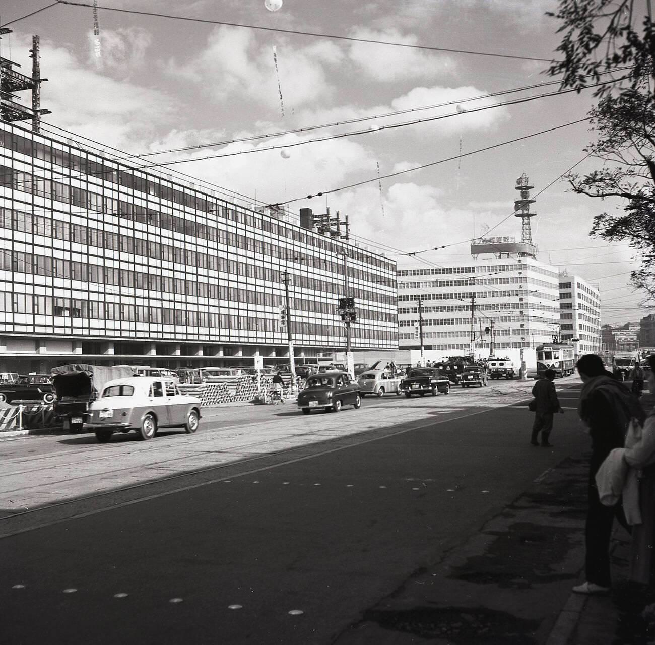 A wide street in Tokyo showing new office blocks, the city centre tram, and motor vehicles, 1950s.
