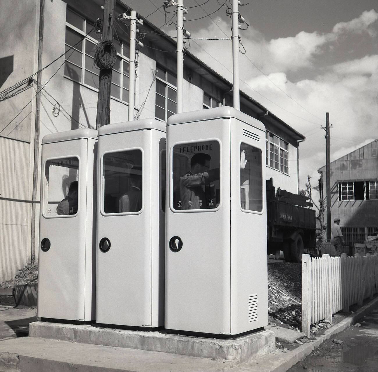 A row of three newly installed public payphones, 1950s.