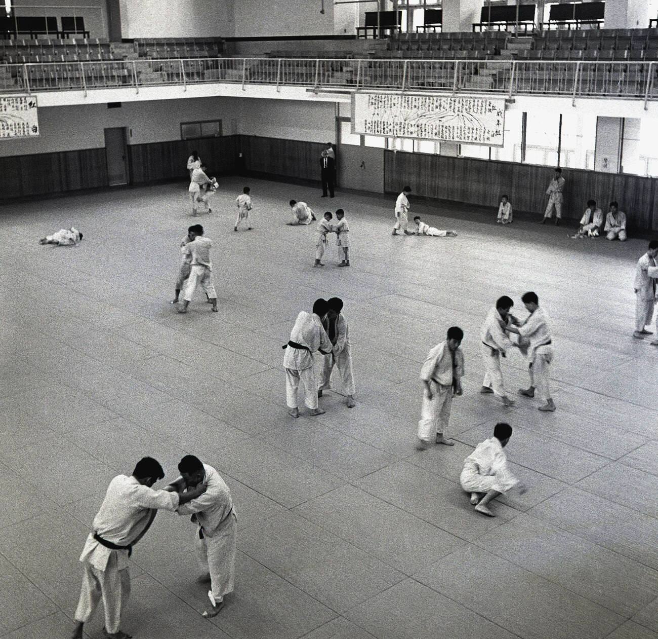 Japanese men doing judo training inside a large sports hall, 1950s.