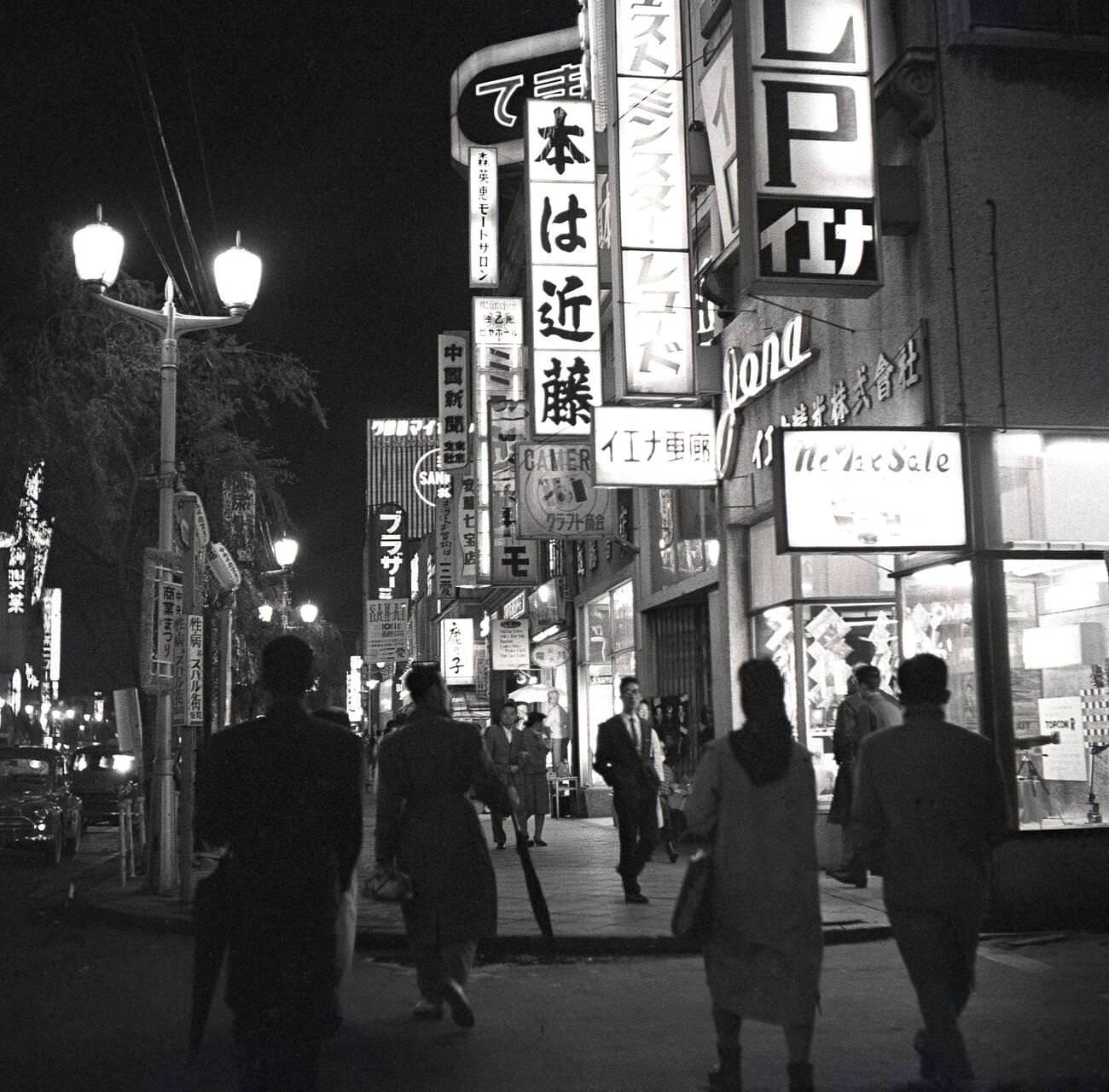 Shop lights and signs light up the city of Tokyo at evening time, 1950s.