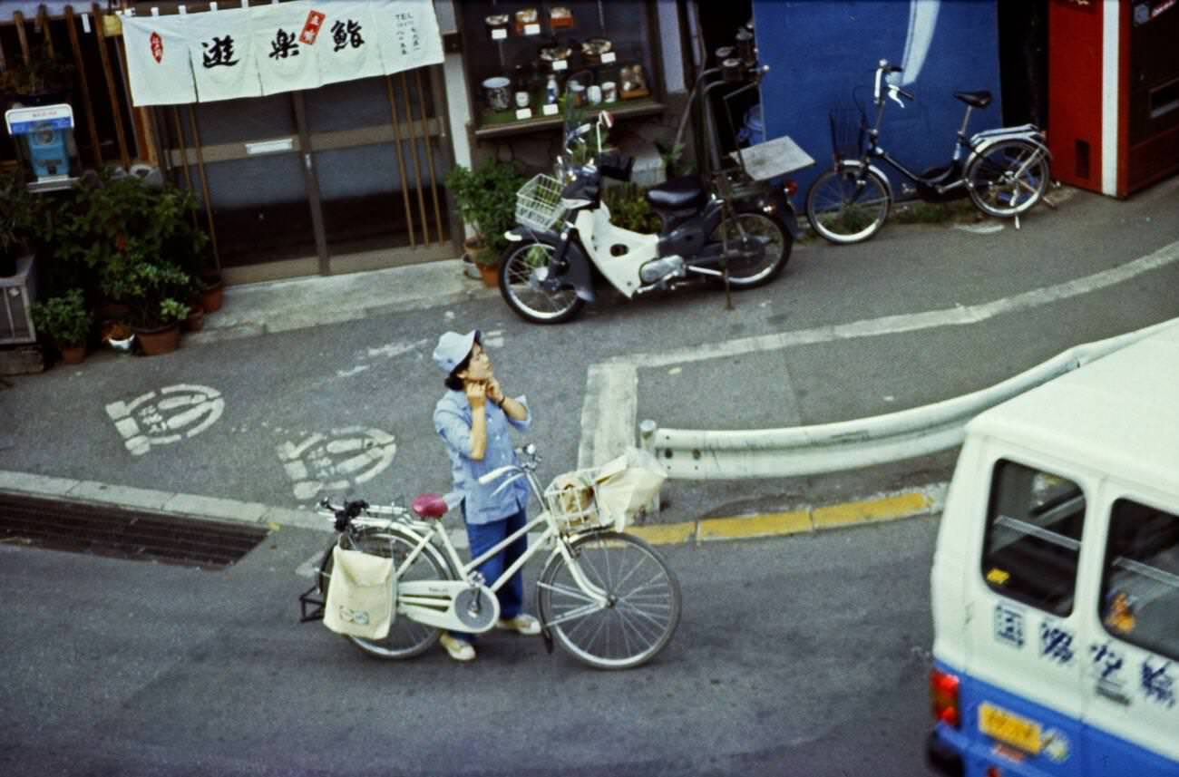 Woman with a bike and shopping on the street, Tokyo, 1970s.