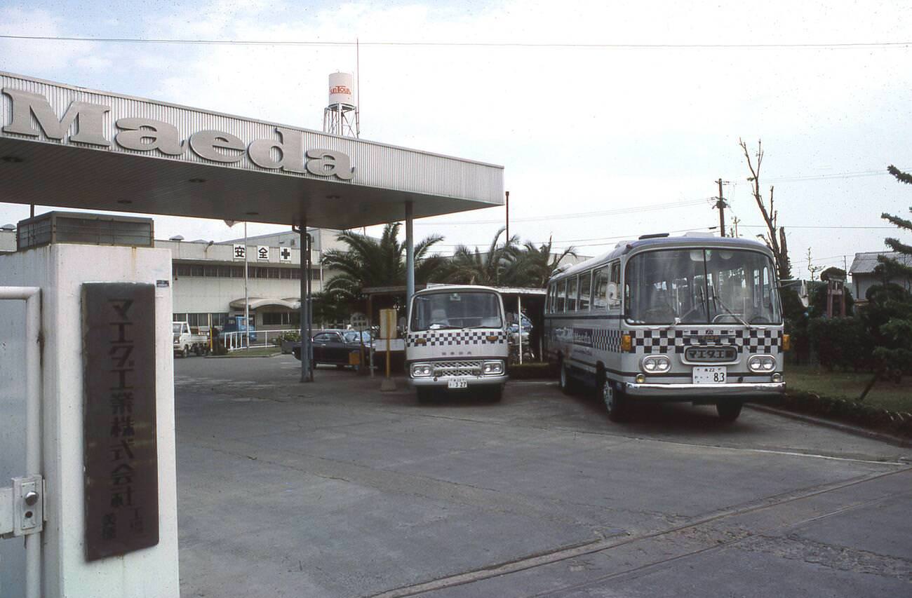 The entrance to the Maeda industrial premises, with the company's branded coaches parked up, 1970s.