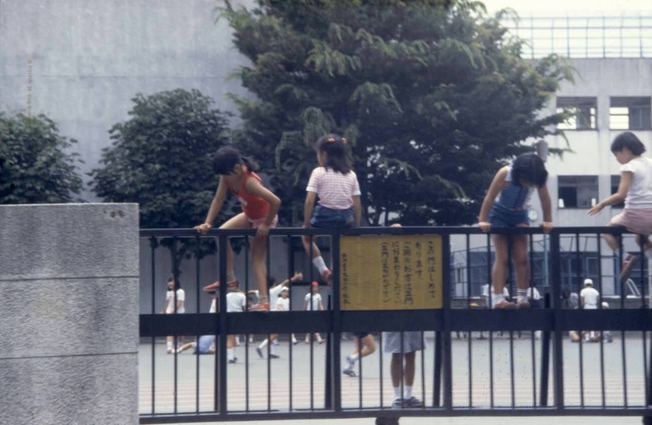 Children climb the school fence, Tokyo, 1970s.