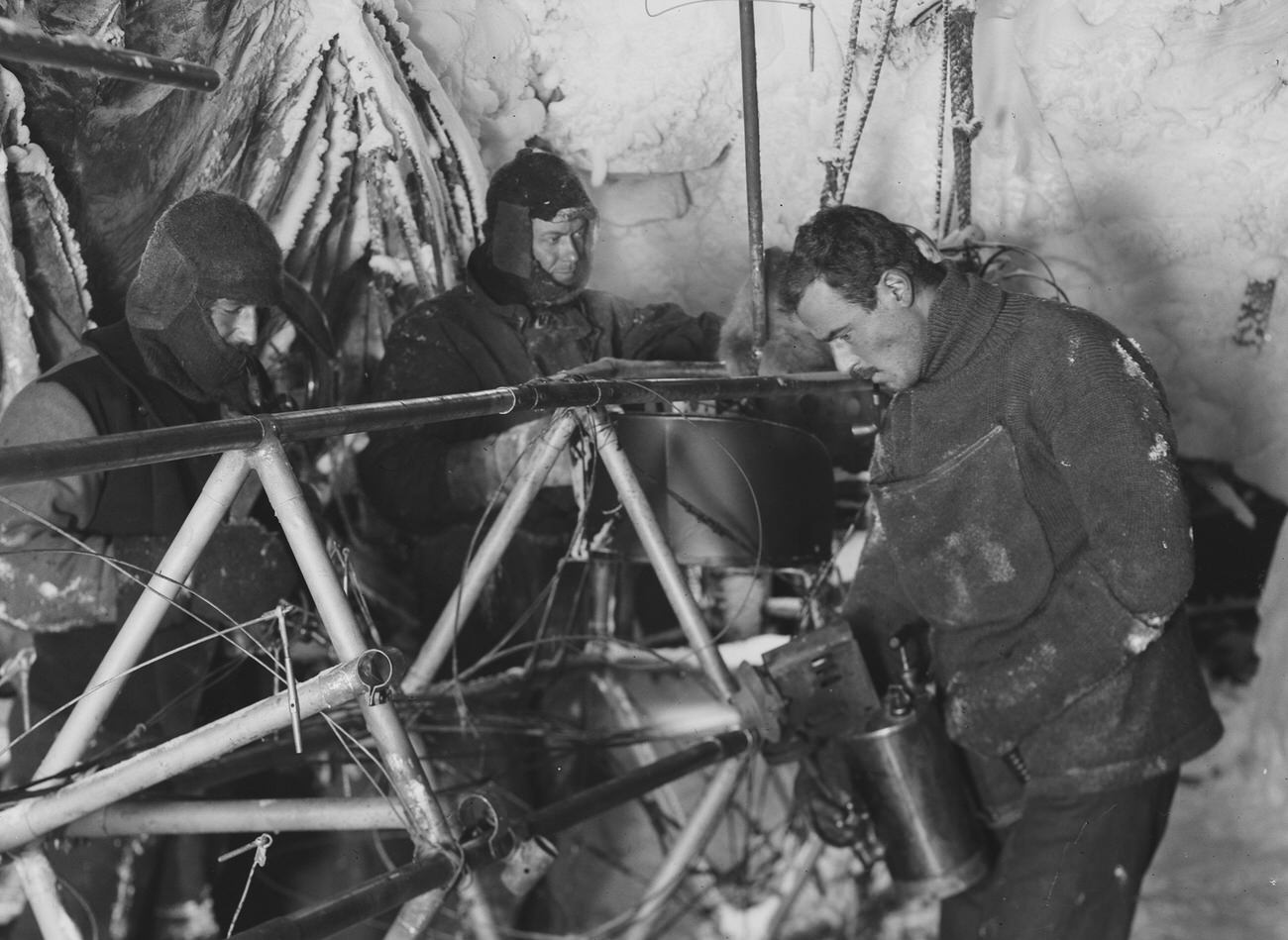 Bickerton repairs the Air-tractor in the Hangar (left to right Bage, Ninnis, Bickerton0, Cape Denison, Antarctica, 1912-1913, by Frank Hurley