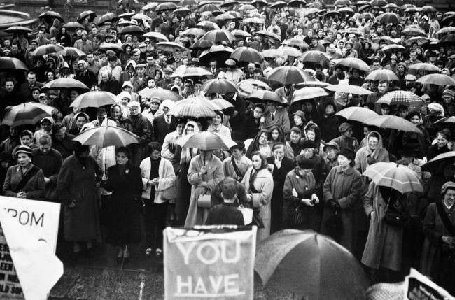 A huge crowd of mostly women sheltered under their umbrellas in Trafalgar Square, London, at a mass meeting of the National Council for the Abolition of Nuclear Weapon Tests, 1957.