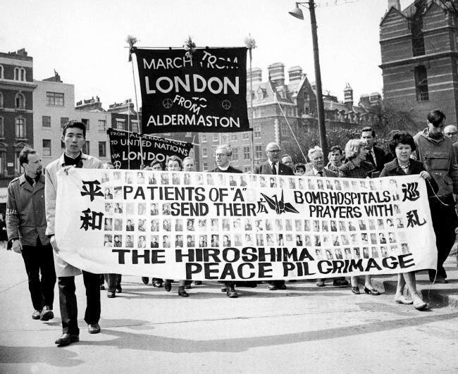 Two survivors of the Hiroshima atomic bomb, 29-year-old nurse Miyoko Matsubara and law student Hirosama Hanabusa, 18, join the column of British nuclear disarmers as the demonstrators file into London's Hyde Park for the mass rally climaxing their Easter March from Aldermaston, 1962.