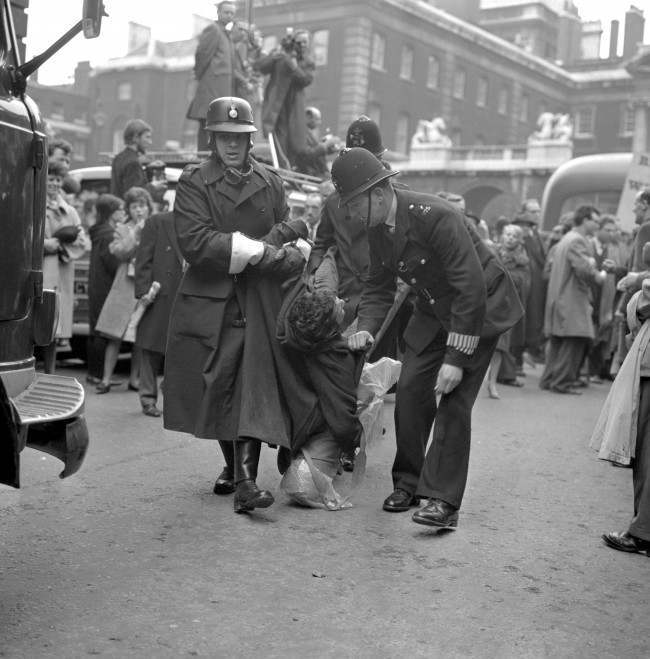 A man gripped by three policemen in Whitehall, when scuffles broke out as police tried to control Aldermaston to London anti-bomb marchers as they passed through on their way to the final rally in Hyde Park, 1963.