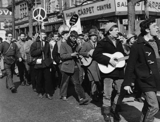 Guitar strumming youths and banner bearers march into London in the 20,000 strong procession of anti a bomb demonstrators protesting against the manufacture of nuclear weapons, 1960.