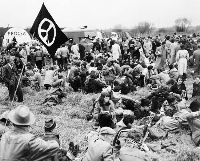 Marchers protesting nuclear bomb tests rest in a field near an airport in London, 1959.