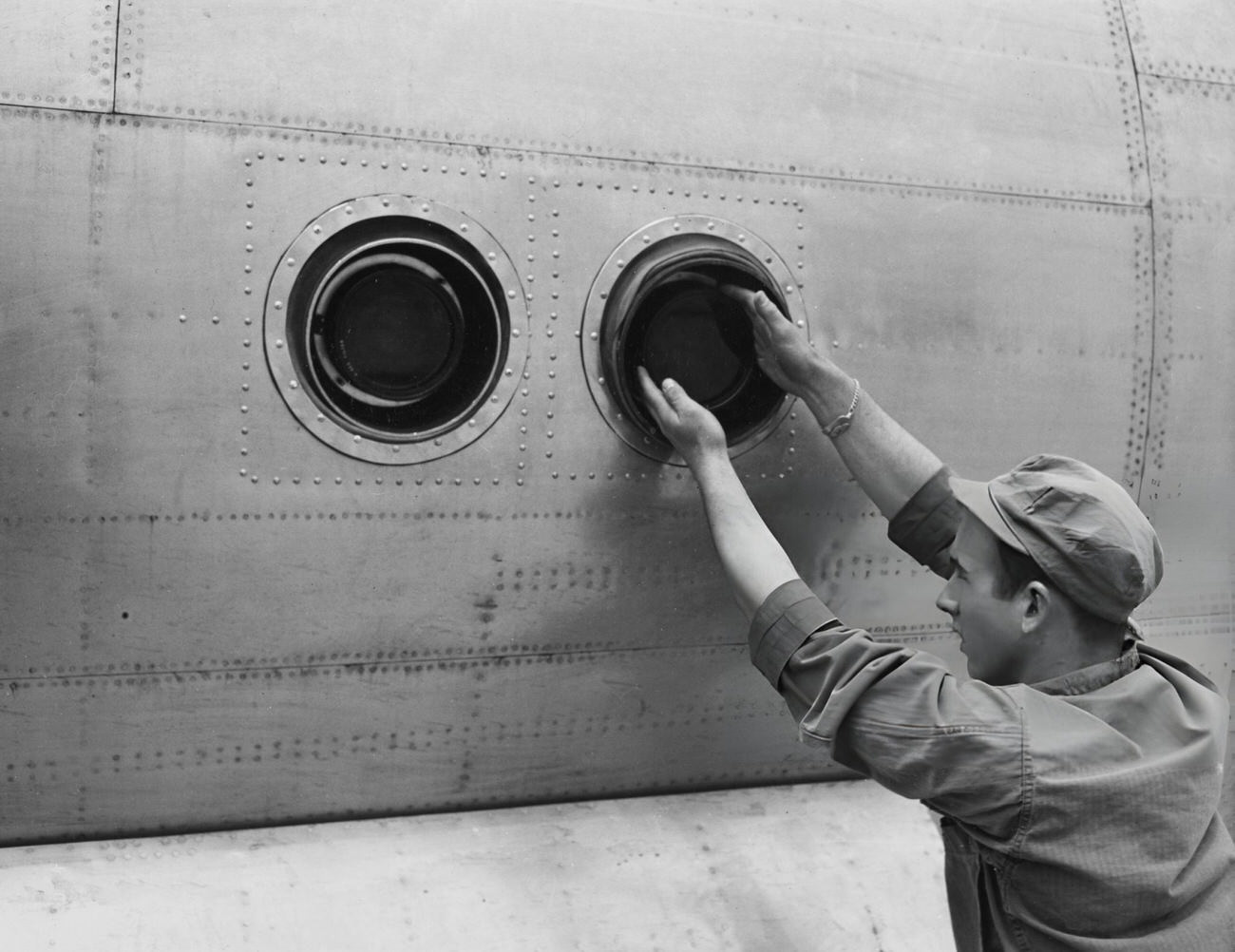 American Private first class Marvin L Cooper tightens the filter on the outer lens surface of two bomb bay K-18 cameras, mounted on an F-13 camera aircraft at Roswell Army Air Field, New Mexico, 1946.