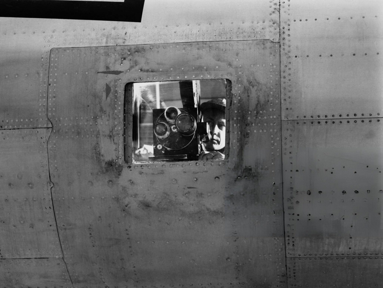 American Army photographer Charles E Nerpel, visible through a camera port as he aims his high-speed Mitchell colour camera during a Joint Army-Navy Task Force demonstration in a converted B-29 aircraft, at Roswell Army Air Field in Roswell, New Mexico, 1946.