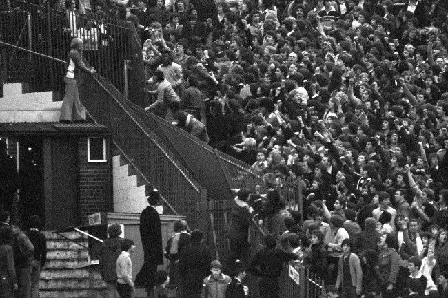 Tottenham Hotspur fans tear down a section of iron railings in a bid to reach Chelsea supporters, 1970s.