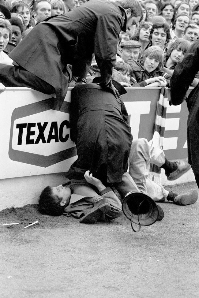 An unruly fan is pinned down by a policeman after trouble erupted before the match, 1970s.