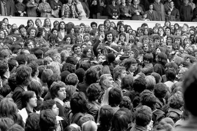 A policeman's helmet goes flying as he wades into the crowd, 1970s.