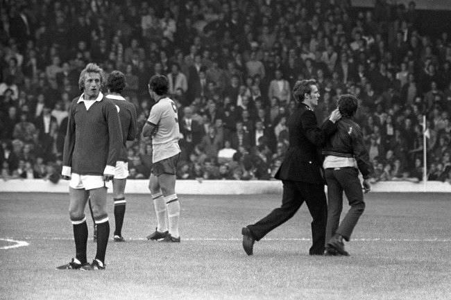 Denis Law waits patiently as a Policeman grabs a youth by his ear, 1970s.